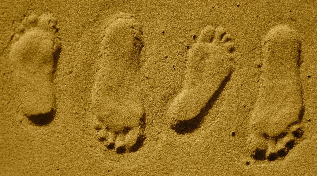 two sets of footprints in sand, as if dancing